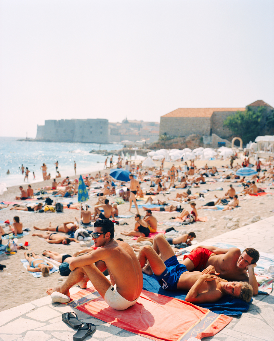 CROATIA, Dubrovnik, Dalmatian Coast, relaxing at East West Beach with the old city of Dubrovnik in the background.