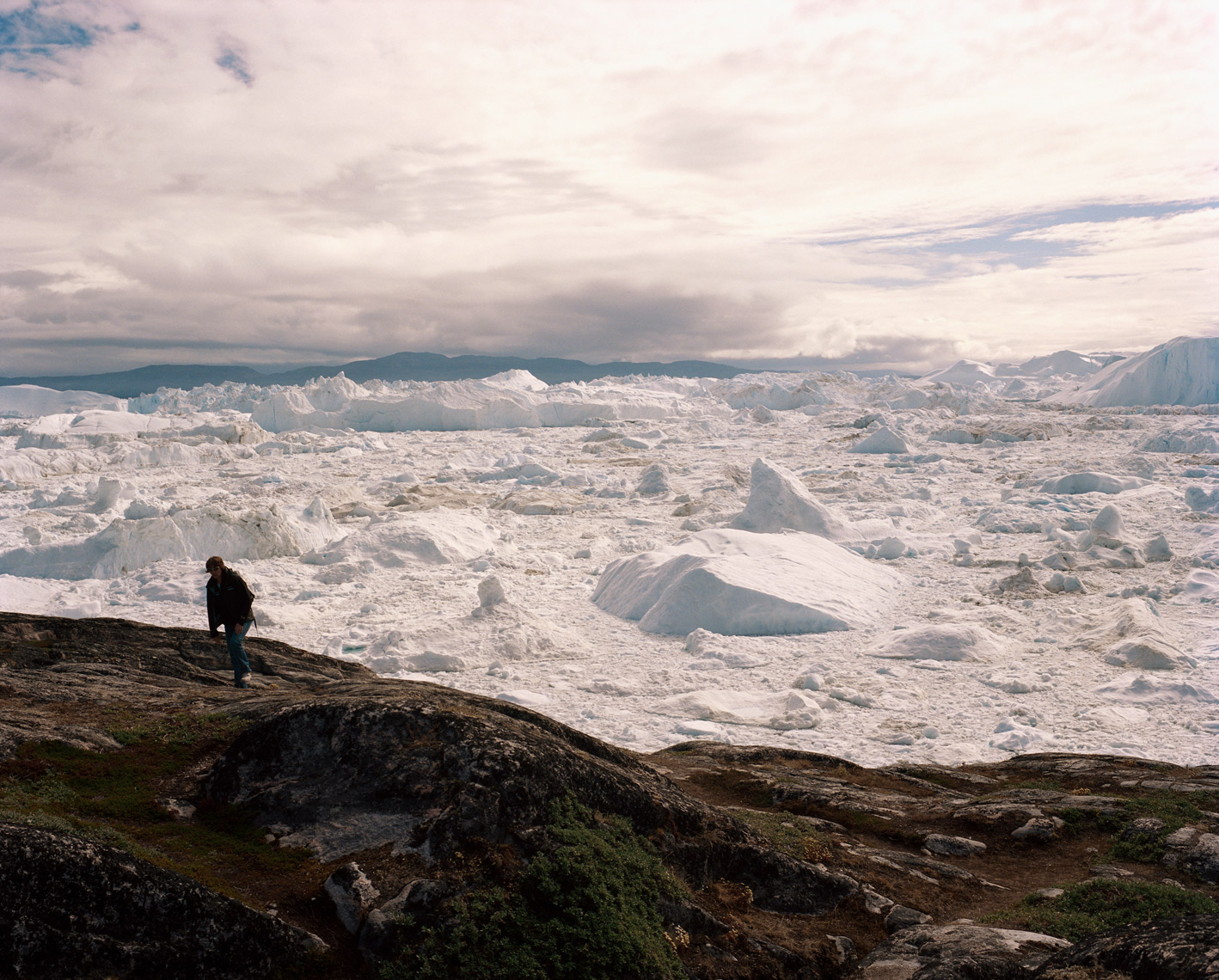 GREENLAND, Ilulissat, Ilullisat Icefjord, woman walking with glaciers in the background