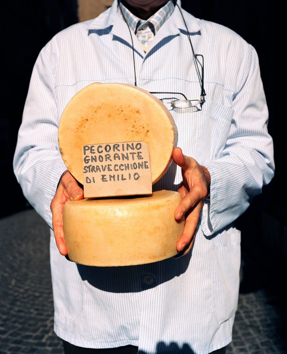 ITALY, Orvieto, Umbria, butcher Emilio Batalocco holding pecorino cheese.