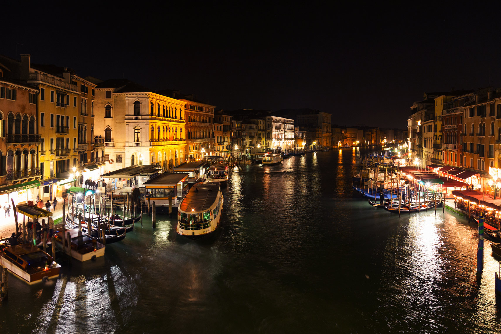 ITALY, Venice. View of the Grand Canal, homes, shops,  and restaurants from the Rialto Bridge at night.